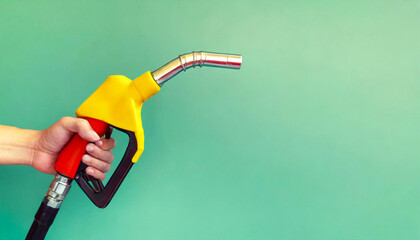 Male hand holding a fuel dispenser isolated on a green background. Banner with copy space - obrazy, fototapety, plakaty