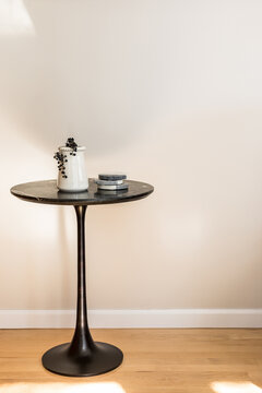 Round dark modern side table with beige wall