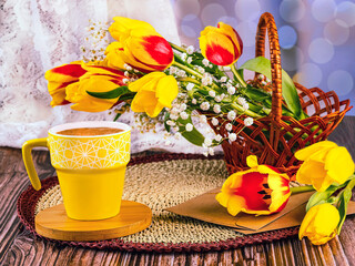 Romantic spring still life. A bouquet of red and yellow tulips in a basket, gypsophila flowers, a...