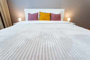 a bed with striped sheets and pillows in a bedroom