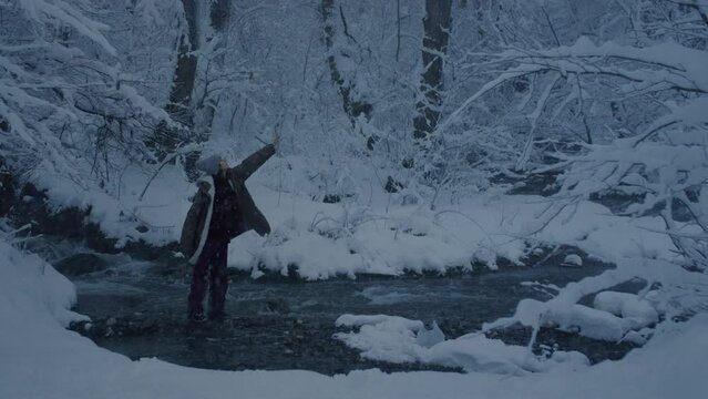 Portrait: A young girl holding a burning signal fire. A woman in a winter forest starts a red rescue flare. Snow on the trees, blue hour. Female person gives a distress signal, snowy weather