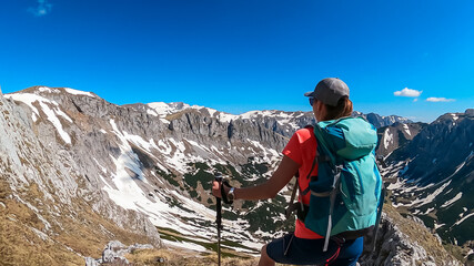 Hiker woman with panoramic view of majestic mountain peak Ringkamp in wild Hochschwab massif, Styria, Austria. Scenic hiking trail in remote Austrian Alps on sunny day. Wanderlust in alpine spring