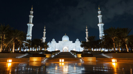 Fototapeta na wymiar Amazing beautiful mosque with palm trees and lights in the night city of Abu Dhabi. Sheikh Zayed Grand Mosque in the dark