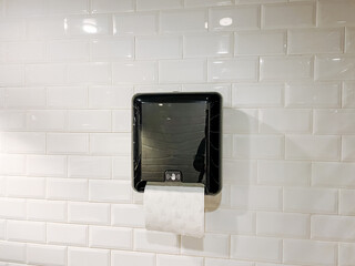 Rectangle gadget mounted on white brick wall black paper towel dispenser