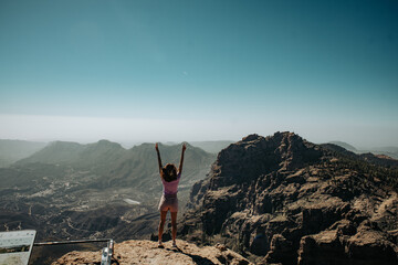 Turystka z podniesionymi rękoma na szczycie góry na wyspie Gran Canaria - obrazy, fototapety, plakaty