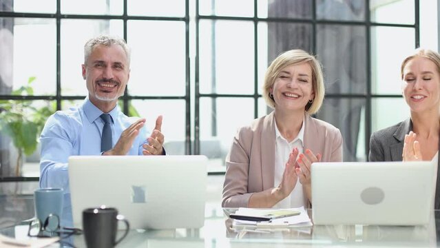 Group of cheerful businesspeople sitting in a row on a presentation and clapping