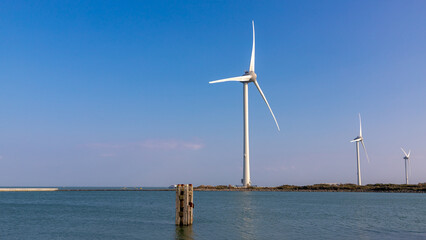 White wind turbine on the dunes with blue sky, The Delta Works is a projects to protect a large area of land around southwest from the sea, Flood protection system, Neeltje Jans, Zeeland, Netherlands.