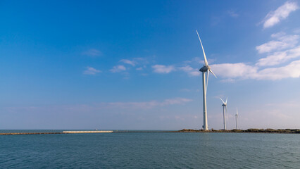 White wind turbine on the dunes with blue sky, The Delta Works is a projects to protect a large area of land around southwest from the sea, Flood protection system, Neeltje Jans, Zeeland, Netherlands.