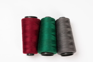 Sewing machine threads, red, green, gray, overlock thread. Industrial threads on a white background, spools of multicolored threads 