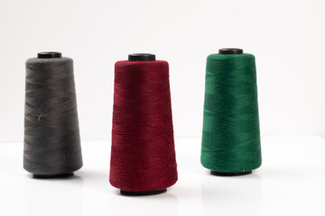 Sewing machine threads, red, green, gray, overlock thread. Industrial threads on a white background, spools of multicolored threads 