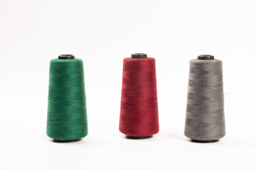 Sewing machine threads, red, green, gray, overlock thread. Industrial threads on a white background, spools of multicolored threads 