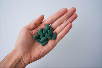 hand with pills green chlorophyll