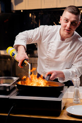 a chef frying different vegetables on a hot frying pan with torch on the stove