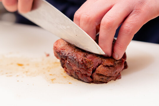 close-up of professional cutting seared beef steak with knife white board