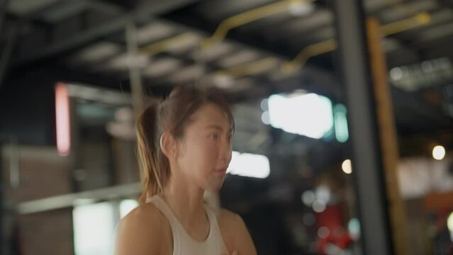 Dynamic image of a focused athletic woman running fast during an indoor workout session at a gym.