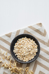 Oatmeal in a plate on a napkin on a white textured background with dry branch.