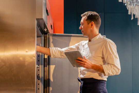 professional kitchen chef looks into the fridge and chooses ingredients for cooking food concept