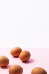 Brown eggs on pink and white background