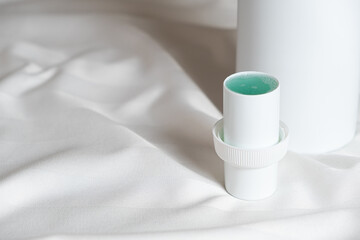 Fototapeta na wymiar Natural liquid laundry detergent on a background of white satin fabric.