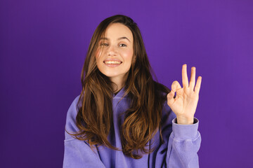 Happy young charming woman showing ok sign with fingers, trying to say that everything is super,...