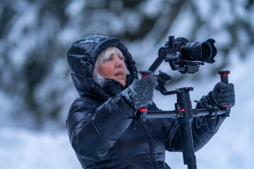 Woman in a down jacket holds a stabilizer with a camera