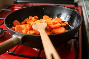 Making dinner at home. Cooking stewed carrot on the frying pan. Photo with selective focus