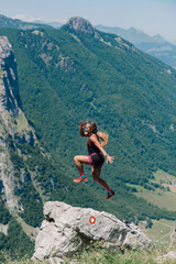 Naklejka na ściany i meble An extreme sportswoman is practicing skyrunning in rocky mountains.