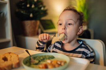 An adorable little boy biting his food while sitting at dining table.