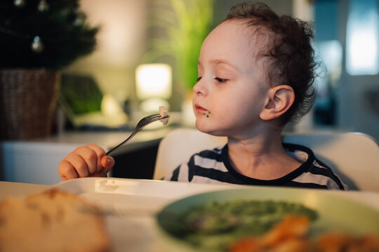 Portrait of a little boy sitting at dining table and eating his lunch.