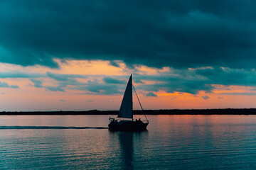silueta de barco de vela navegando en laguna de bacalar quintana roo mexico al amanecer