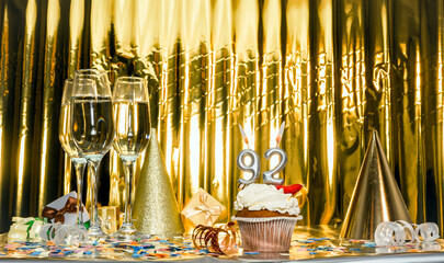 Background date of birth with number 92. Scenery festive glasses of champagne, anniversary in golden color. Copy space. Happy birthday postcard.