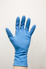 Man's hand wearing nitrile gloves on white background. Person in blue rubber gloves holding something against white background, closeup on hand. 