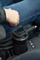 Thermal mug in the cup holder of the car. Black thermal mug