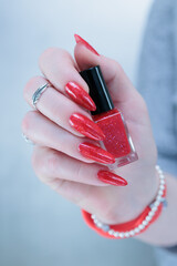 Female hand with long nails and a bright red nail polish