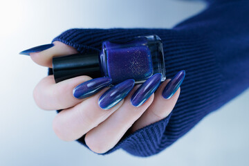 Woman's beautiful hand with long nails and bright blue manicure