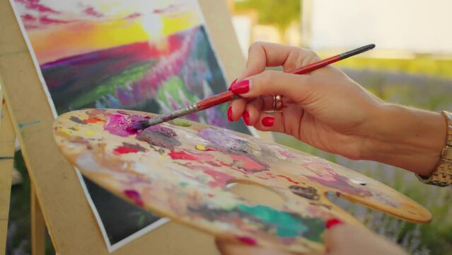 Close-up of artist's hand with a paintbrush over canvas. Vibrant painting process. Creativity and art expression concept for design and print with copy space.