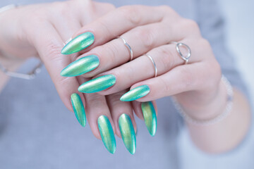 Female hand with long nails and light green and blue turquoise manicure 