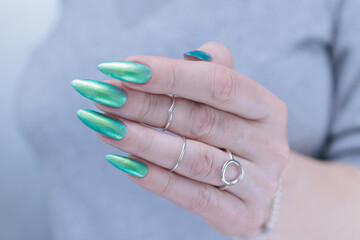 Female hand with long nails and light green and blue turquoise manicure 