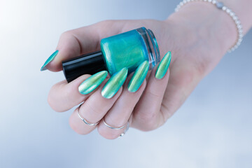 Female hand with long nails and light green and blue turquoise manicure 