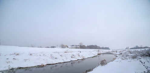 Rzeka Kamienna płynąca przez swą dolinę pokrytą śniegiem pod mglistym "śnieżnym" niebem . Dzikie zakątki miasta - Ostrowiec. © Grzegorz