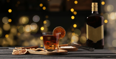 Glass of cold Old Fashioned Cocktail on black wooden table in bar