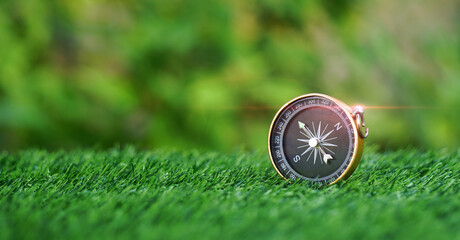 Gold compass on green grass in the garden background with sunshine, navigation concept, learning...