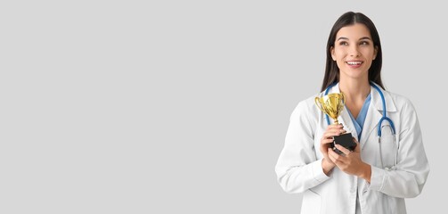 Female doctor with trophy cup on light background with space for text