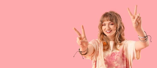 Female hippie showing peace gesture on pink background with space for text