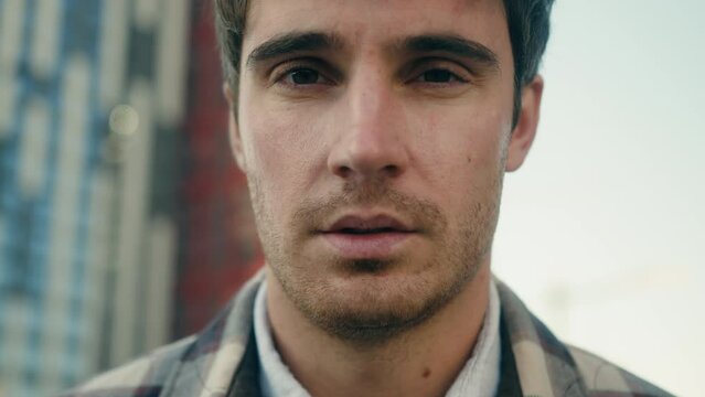 Close up man face Caucasian 30s guy headshot of serious pensive unhappy calm eyesight male person young gen z model handsome businessman looking at camera front sad gaze in city outdoors head portrait