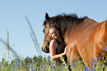Frau mit Pferd im Blumenfeld
