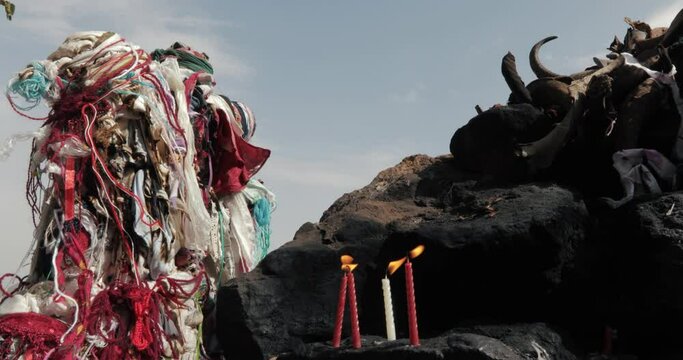 Candles were lit and erected for wishes. He's standing on a rock. Cloths tied to make wishes and horns of sacrificed animals can be seen.