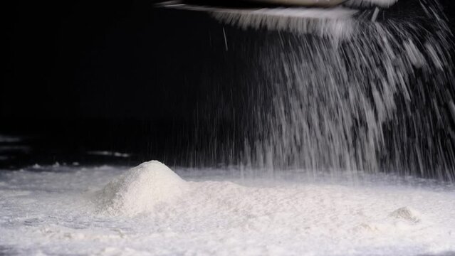 I sprinkle flour on a black background, in a large layer. Baking flour.