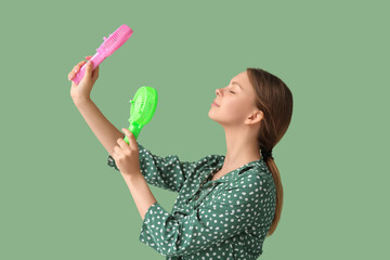 Beautiful young woman with handheld mini fans on green background