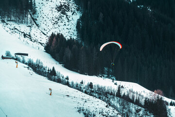 A paraglider soars over a snowy landscape, embodying the concept of freedom and adventure. The...